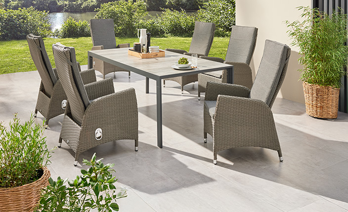 Ein graues Gartenmöbelset aus einem Tisch und Stühlen steht auf einer Terrasse.